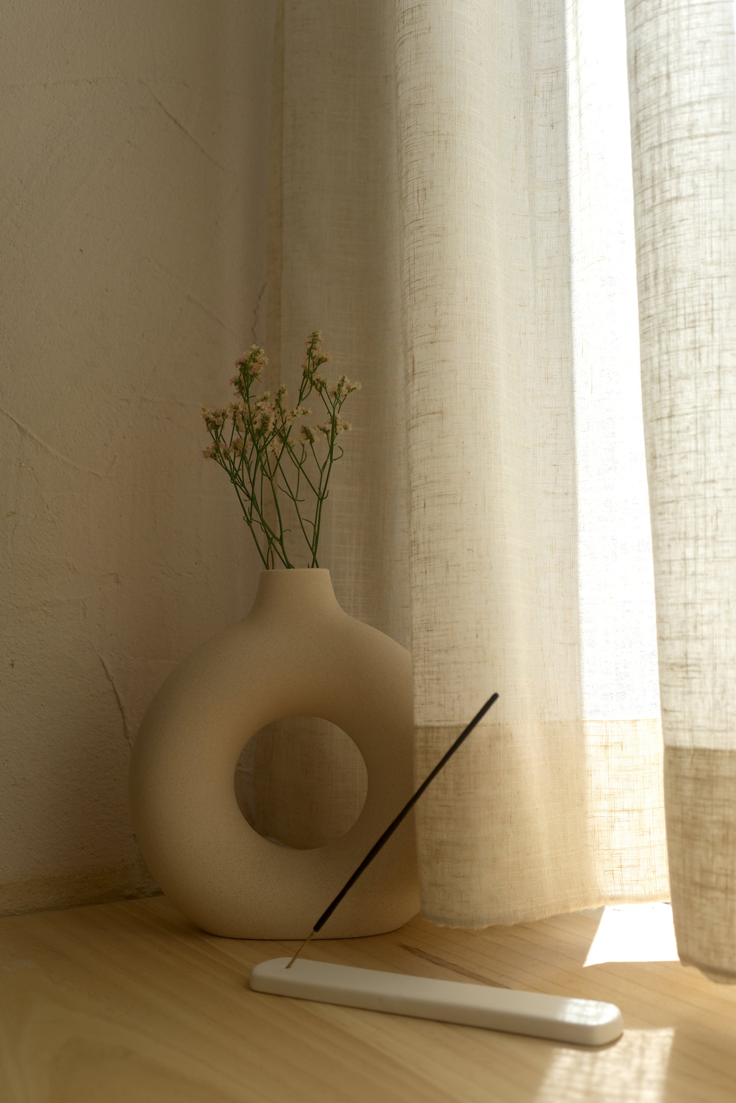 incense holder and incense in front of a beautiful vase with flowers